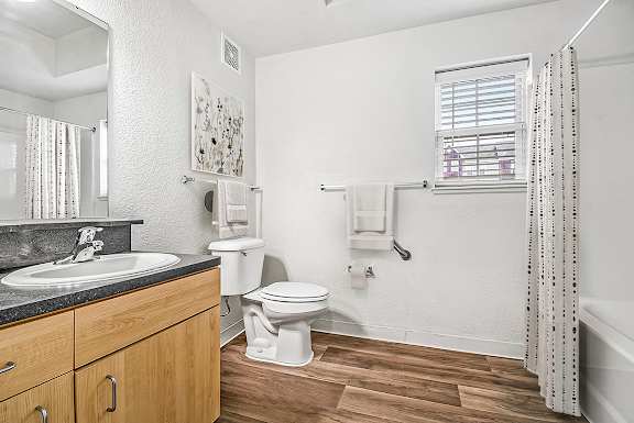 A bathroom with a toilet, sink, and a window at Lynbrook Apartments and Townhomes, Elkhorn, NE, 68022