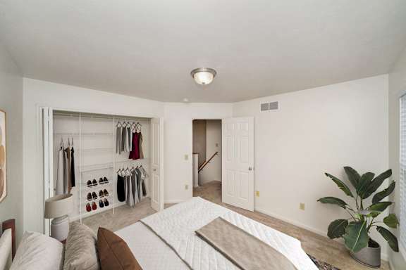 A bedroom with a bed, a closet, and a plant at Lynbrook Apartments and Townhomes, Elkhorn, 68022