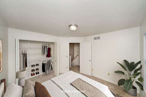 A bedroom with a bed, and a closet with wardrobe organizers at Lynbrook Apartments and Townhomes, Elkhorn, 68022