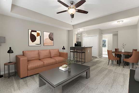 A living room with a couch, a coffee table, and a ceiling fan at Lynbrook Apartments and Townhomes in Elkhorn, Nebraska
