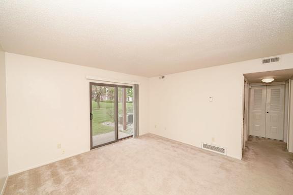 A  living room with a sliding glass door leading to a patio at Madeira Apartments in Kalamazoo, MI