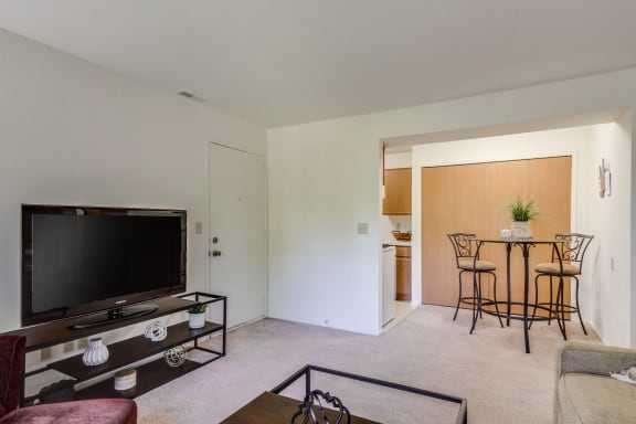 a living room with a flat screen tv and a dining room table in the background  at Sycamore Creek Apartments, Lake Orion