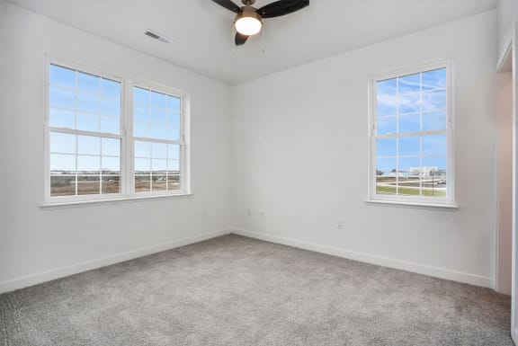 an empty room with two windows and a ceiling fan at Meadowbrooke Apartment Homes, Michigan
