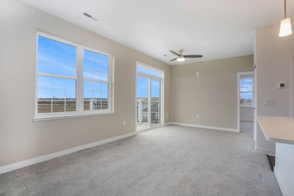 an empty living room with a ceiling fan and large windows at Meadowbrooke Apartment Homes, Grand Rapids