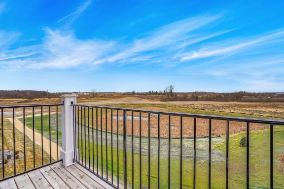a view of a field from a balcony with a blue sky at Meadowbrooke Apartment Homes, Grand Rapids