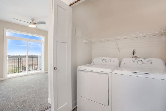 a white laundry room with two washes and a dryer at Meadowbrooke Apartment Homes, Grand Rapids