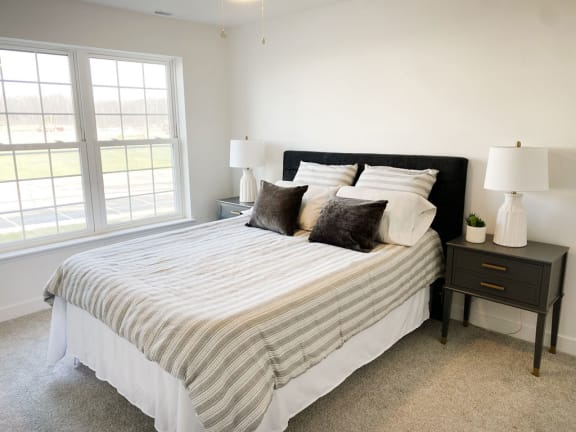 a bedroom with a bed and two nightstands and a window at Meadowbrooke Apartment Homes, Michigan, 49512