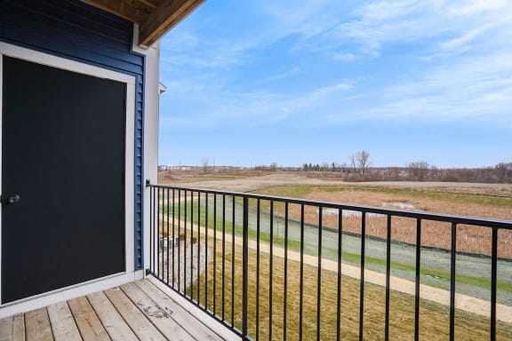 the view from the deck of a home with a gate and a field at Meadowbrooke Apartment Homes, Grand Rapids