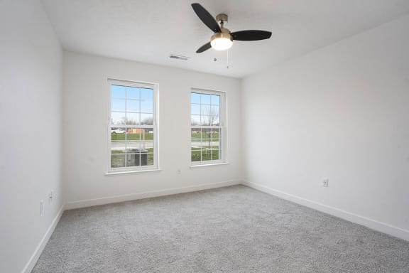 an empty living room with a ceiling fan and two windows at Meadowbrooke Apartment Homes, Grand Rapids, MI, 49512