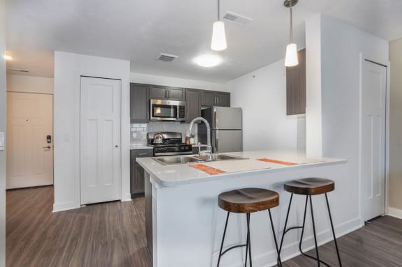 a kitchen with a counter top with two stools at Meadowbrooke Apartment Homes, Grand Rapids, MI