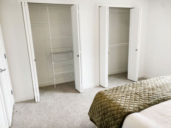 a bedroom with closet doors and a bed at Meadowbrooke Apartment Homes, Michigan