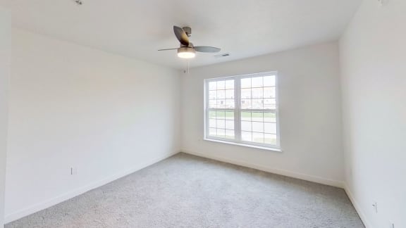 an empty living room with a window and a ceiling fan at Meadowbrooke Apartment Homes, Michigan