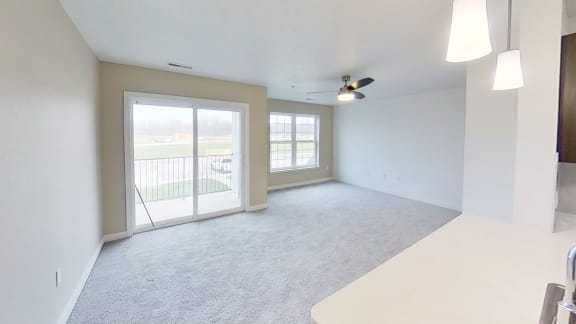 an empty living room with sliding glass doors to a balcony at Meadowbrooke Apartment Homes, Grand Rapids