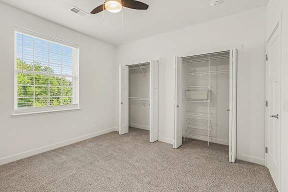 A bedroom with a ceiling fan and a window with blinds at Meadowbrooke Apartment Homes in Grand Rapids, MI 49512