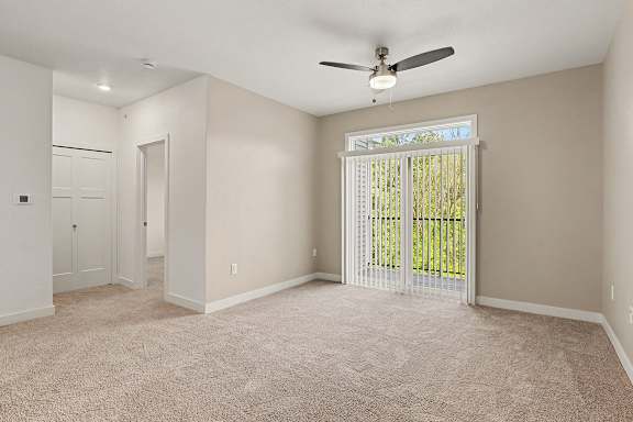 A living room with a ceiling fan and carpeted floor at Meadowbrooke Apartment Homes in Grand Rapids, MI 49512