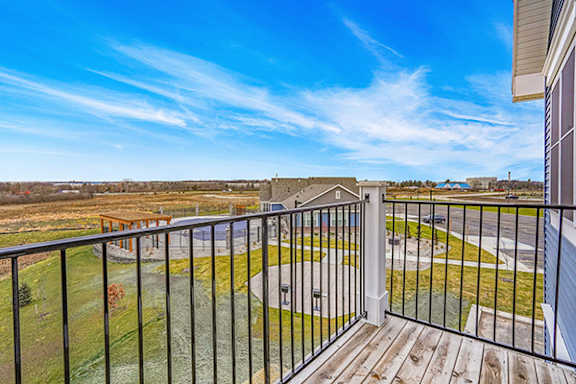 A balcony with a black railing overlooks a grassy area at Meadowbrooke Apartment Homes in Grand Rapids, MI 49512
