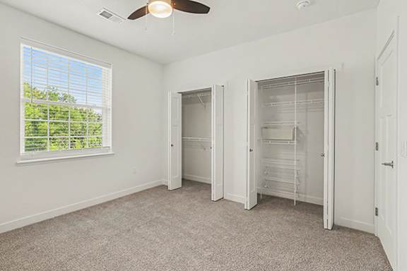 A bedroom with a ceiling fan and a window with blinds at Meadowbrooke Apartment Homes in Grand Rapids, MI