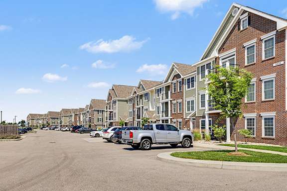 A large apartment building with cars parked in front at Meadowbrooke Apartment Homes in Grand Rapids, MI