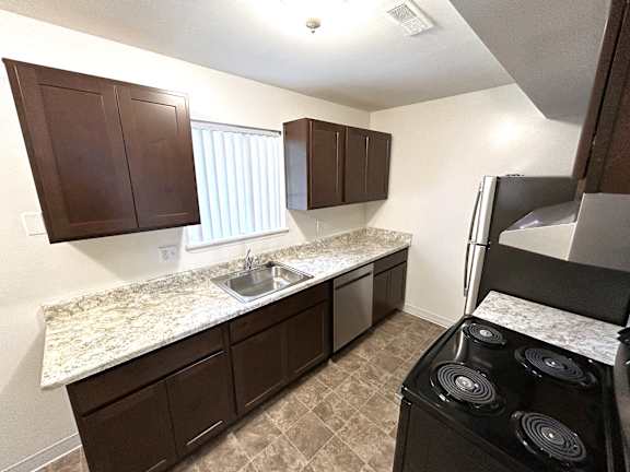 A kitchen with brown cabinets and a granite countertop.