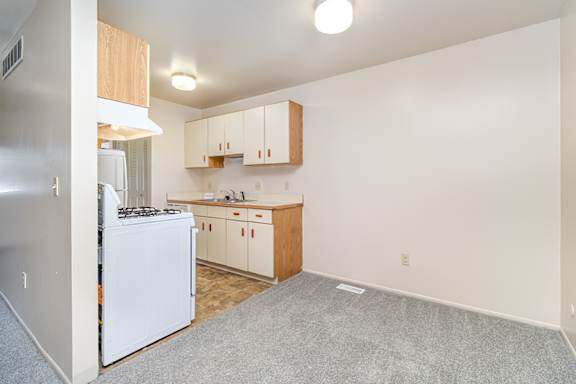 A galley style kitchen with white appliances and wooden cabinets at Mount Royal Townhomes in Kalamazoo, MI