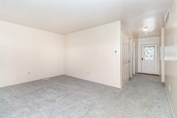 An entryway and living room with a carpeted floor at Mount Royal Townhomes in Kalamazoo, MI