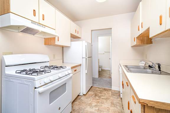 A kitchen with a white stove and cabinets at Mount Royal Townhomes in Kalamazoo, MI