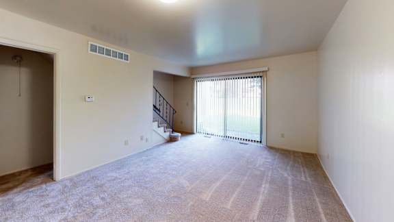 A living room with a carpeted floor and a slider to a private patio at Mount Royal Townhomes, Kalamazoo, MI