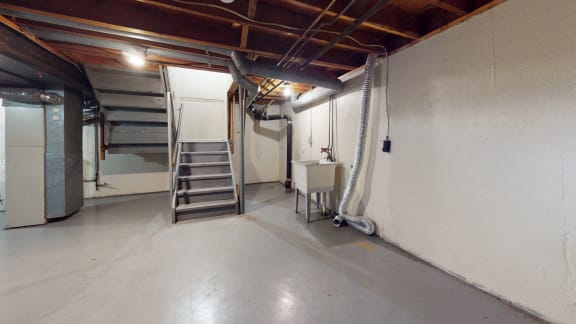 an empty basement with a staircase and a sink