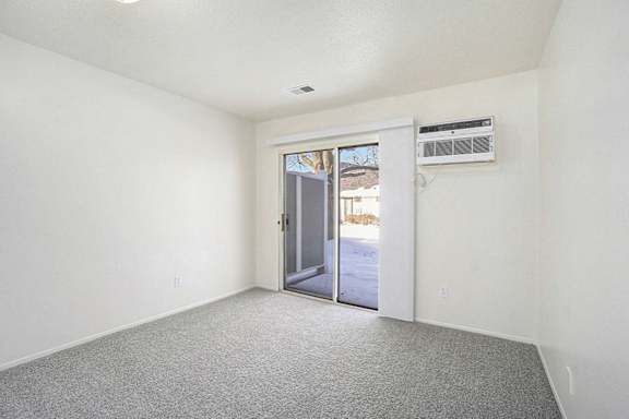 a bedroom with a slider to a semi private patio at Newport Village Apartments, Portage, MI