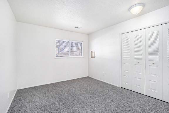 An upgraded bedroom with a window and large closet at Newport Village Apartments, Portage, MI