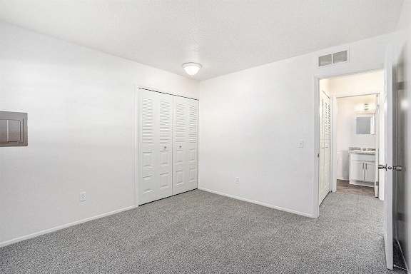 A spacious bedroom with plush carpet and a closet at Newport Village Apartments, Portage, MI