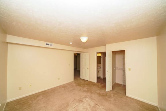 an empty living room with carpet and a hallway to a bathroom at North Pointe Apartments, Elkhart, IN