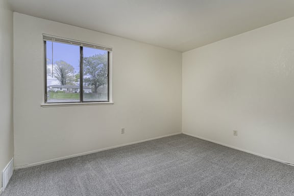 a bedroom with a window and carpeted floor a bedroom with a window and carpeted floor at Normandy Village Apartments, Michigan City, Indiana