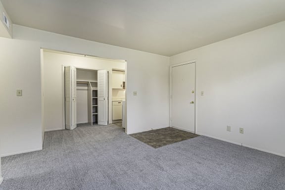 an empty living room with white walls and carpet and a closet a living and dining room with a closet and carpet at Normandy Village Apartments, Michigan City, IN, 46360