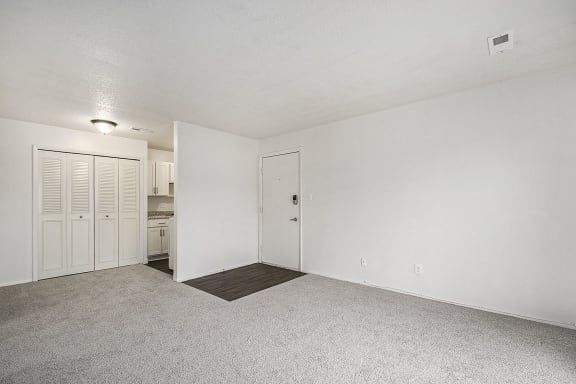 an empty living room and kitchen with white walls and carpet an empty living room and kitchen with white walls and carpet at Normandy Village Apartments, Michigan City, IN