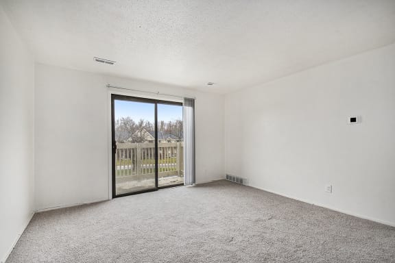 an empty living room with a sliding glass door to a balcony an empty living room with a sliding glass door to a balcony at Normandy Village Apartments, Michigan City, IN, 46360