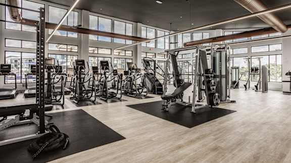 A gym with a variety of equipment including treadmills, weights, and exercise machines.