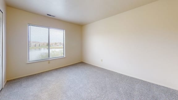 an empty room with a window and carpeting  at Oak Shores Apartments, Oak Creek, Wisconsin