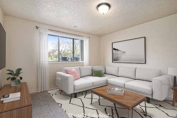 A garden style living room with a white couch, a coffee table, and a large window at Old Farm Apartments, Elkhart, 46517