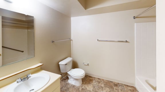 a bathroom with a toilet and a sink and a mirror at Orchard Lakes Apartments, Toledo, Ohio