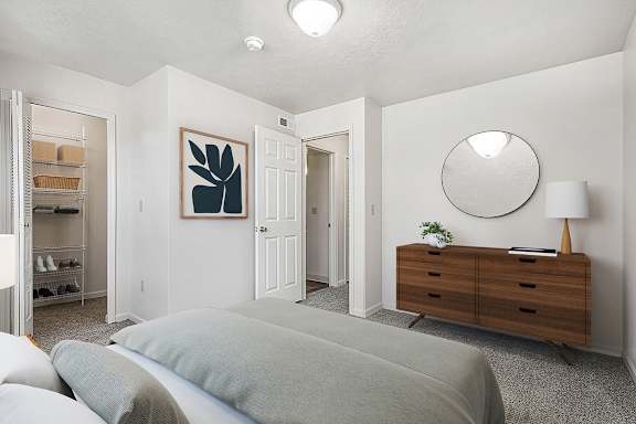 A bedroom with a grey bed and a walk-in closet with organizers at Orchard Lakes Apartments, Toledo, 43615