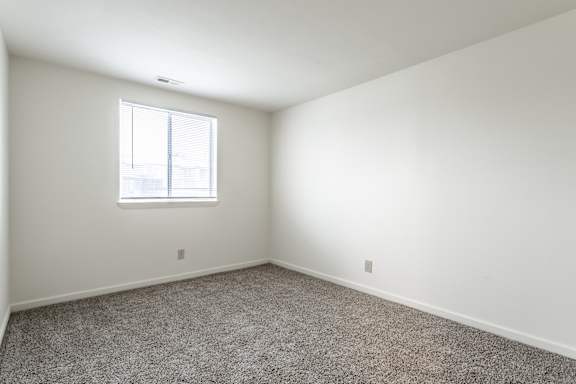 A room with a carpeted floor and a window at Pheasant Run Apartments, Indiana, 47909