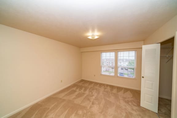 an empty living room with a closet and a window  at Pine Knoll Apartments, Michigan