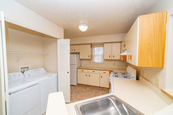 a kitchen with a washer and dryer and a sink  at Pine Knoll Apartments, Battle Creek, MI