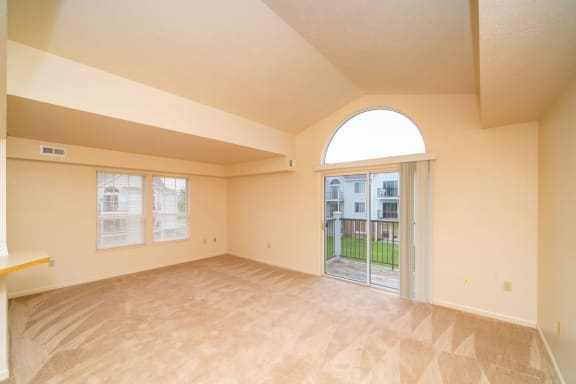 an empty living room with a door to a patio  at Pine Knoll Apartments, Battle Creek