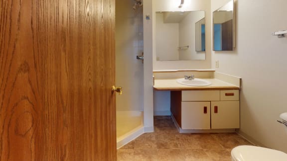 a bathroom with a toilet sink and a mirror at Pine Knoll Apartments, Battle Creek, MI, 49014