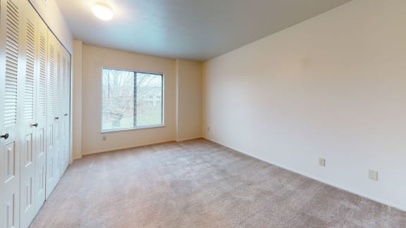 an empty living room with a window and a closet at Pine Knoll Apartments, Battle Creek, MI