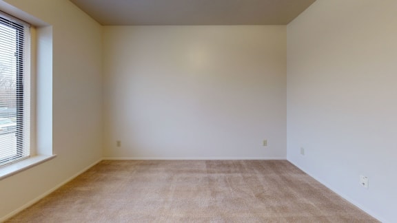 a empty room with a large window and carpet  at Pine Knoll Apartments, Battle Creek, MI