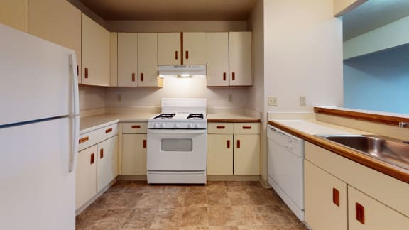 a kitchen with white appliances and white cabinets at Pine Knoll Apartments, Battle Creek