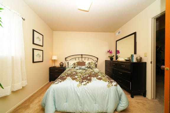 a bedroom with a bed and a dresser  at Pine Knoll Apartments, Battle Creek, MI, 49014